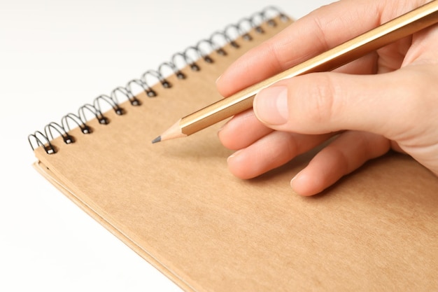 A mão escreve em um caderno com um lápis de perto