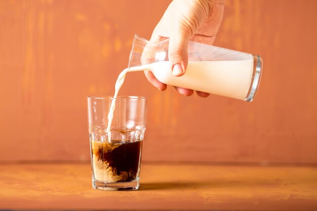 A mão está derramando leite no café em estúdio com espaço de cópia