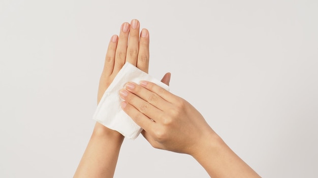 A mão está segurando lenço de papel e toalhetes no fundo branco