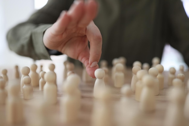 A mão feminina empurra figuras de madeira de homens na mesa, perseguindo o conceito de aproximação em