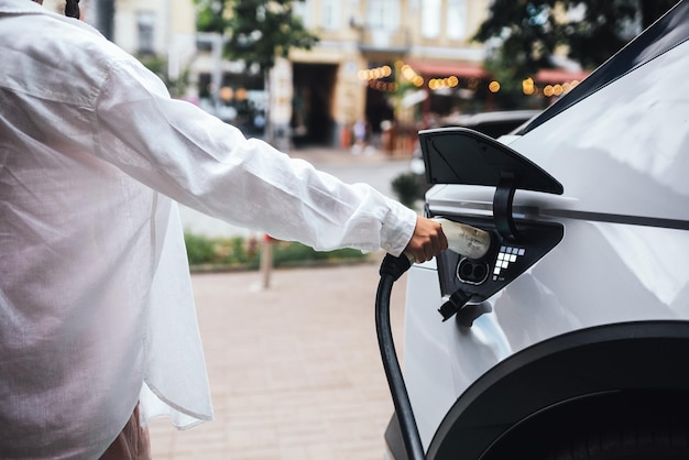 A mão humana está segurando o bocal de carregamento de carro elétrico