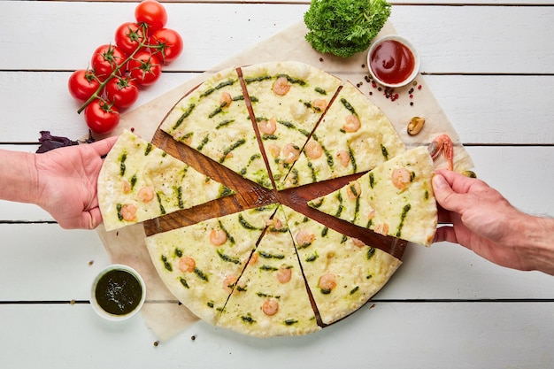 A mão humana leva Pizza saborosa recém-assada com camarão e queijo mussarela servido em fundo de madeira com molho de tomate e ervas Conceito de entrega de comida Menu de restaurante