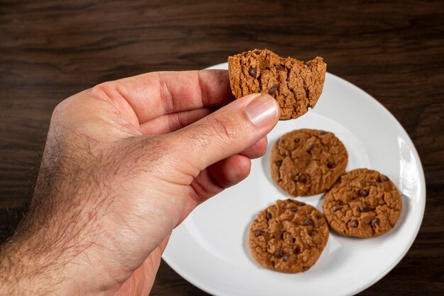 Foto a mão masculina pega um biscoito de chocolate da vista superior foco seletivo de fundo de madeira