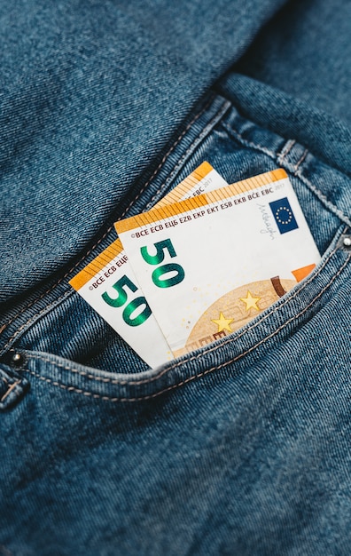 A mão que coloca notas de euro em um bolso de jeans