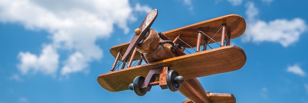 A mão segura um avião de madeira no fundo da nuvem