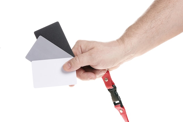 A mão segura um conjunto de cartões cinza para ajustar o equilíbrio de branco em um fundo branco, um modelo para designers