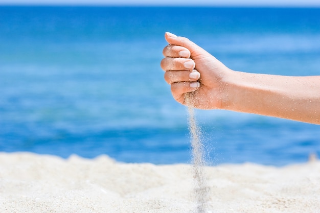 A Mãos despejam areia do mar na natureza em uma jornada. Férias na areia do mar o tempo passa.