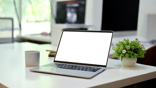 A maquete da tela branca do laptop está em uma imagem de closeup da mesa de escritório moderna
