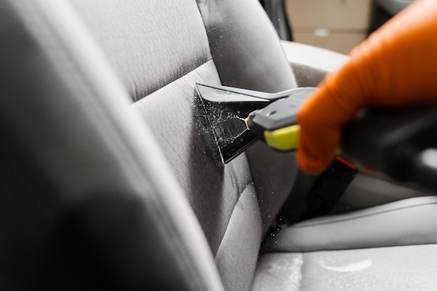 A máquina extratora de limpeza a seco fechada está pulverizando água e detergente no assento têxtil dentro do carro A lavanderia a seco está usando a máquina de extração para remover manchas e sujeira dos assentos têxteis