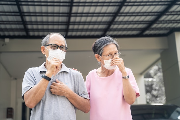 Foto a máscara vestindo dos pares superiores mais velhos asiáticos para evita a poluição do ar da pm 2.5 do crepúsculo.