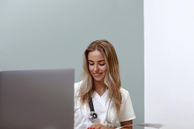 A médica sorridente está sentada na mesa