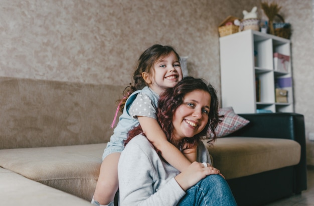 A menina abraça a mãe feliz pelo pescoço e sorri alegremente juntas. um grande retrato. feliz maternidade