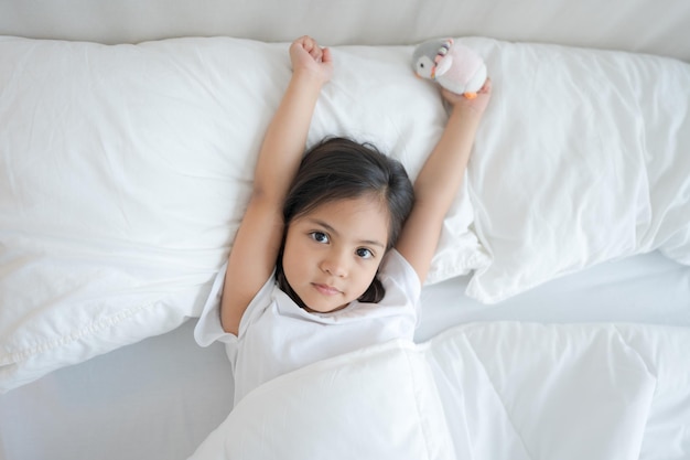 A menina acorda em um confortável quarto branco