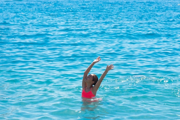 A menina adolescente nova nada e tem o divertimento no mar