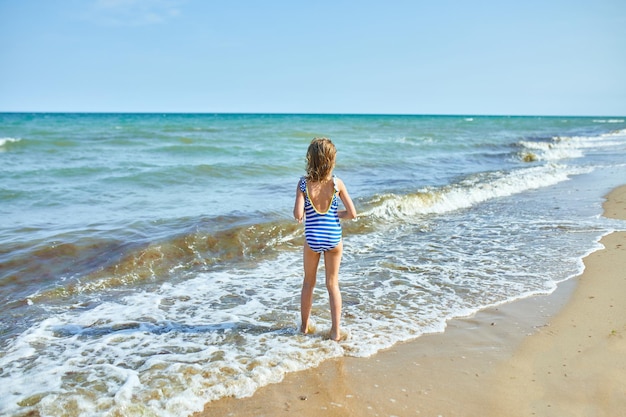 A menina alegre feliz corre na praia