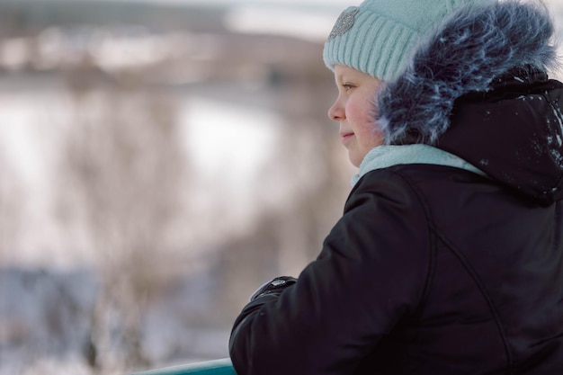 A menina anda ao ar livre no dia nevado do inverno dentro