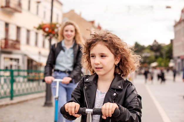 A menina anda de scooter pela primeira vez junto com a mãe