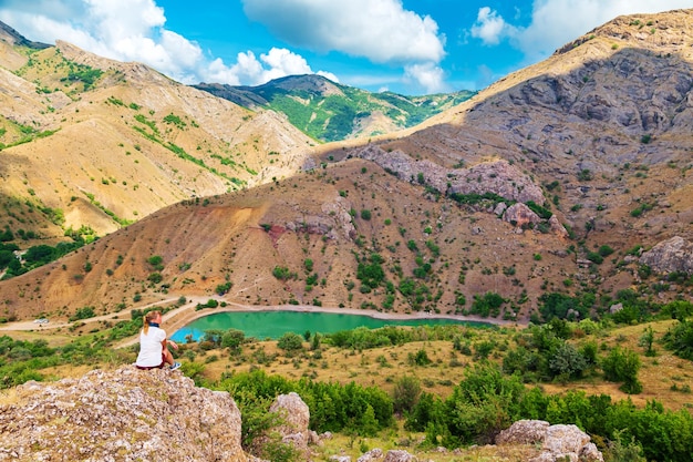 A menina aprecia a vista do lago de montanha