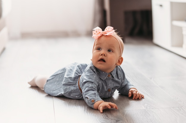 Foto a menina aprende a engatinhar no chão da sala.