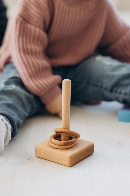 A menina aprende as cores brincando com figuras humanas coloridas de brinquedos cilíndricos de madeira e colocando-as em copos da cor apropriada A criança fica feliz por ter concluído a tarefa corretamente