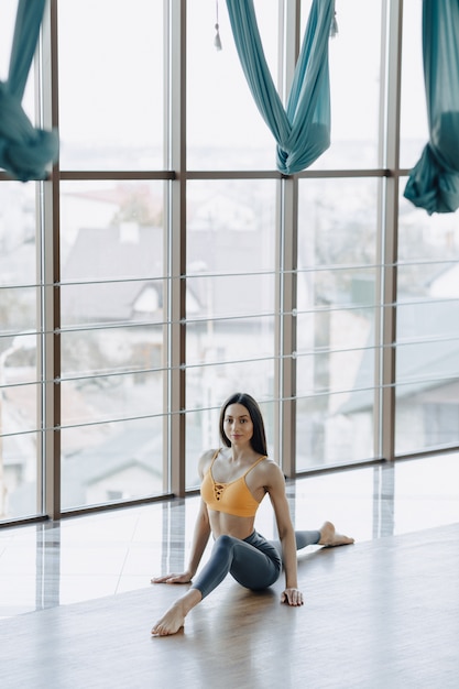 A menina atrativa nova que faz a aptidão exercita com ioga no assoalho. janelas panorâmicas