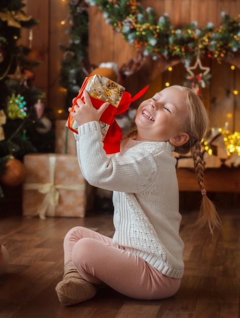 Foto a menina bonita abre um presente de natal.