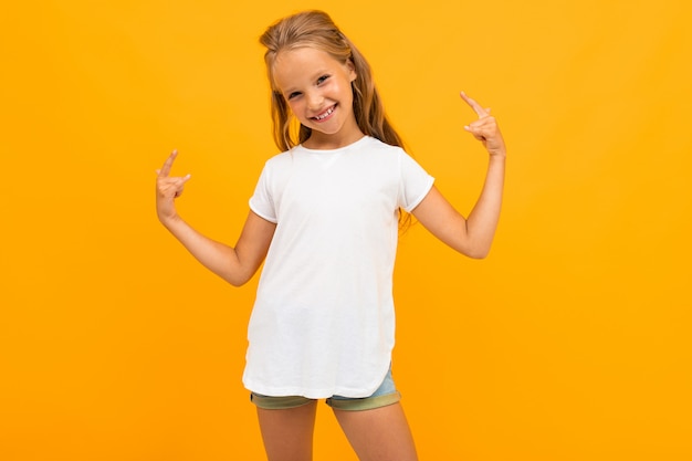 A menina bonita em um amarelo ri em uma camiseta branca