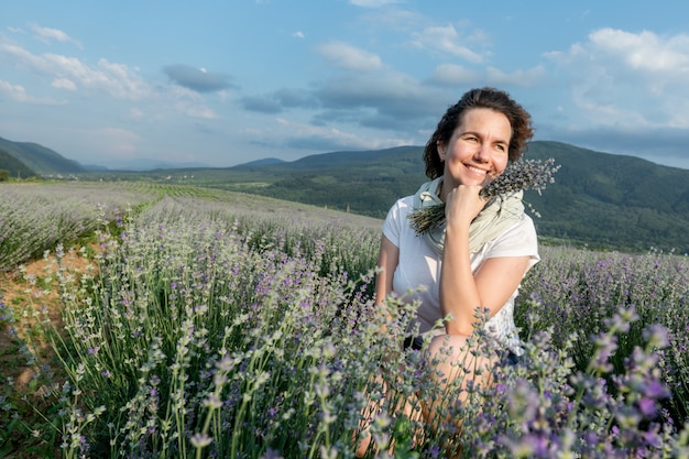 A menina bonita em um campo de lavanda aprecia a paisagem e o cheiro