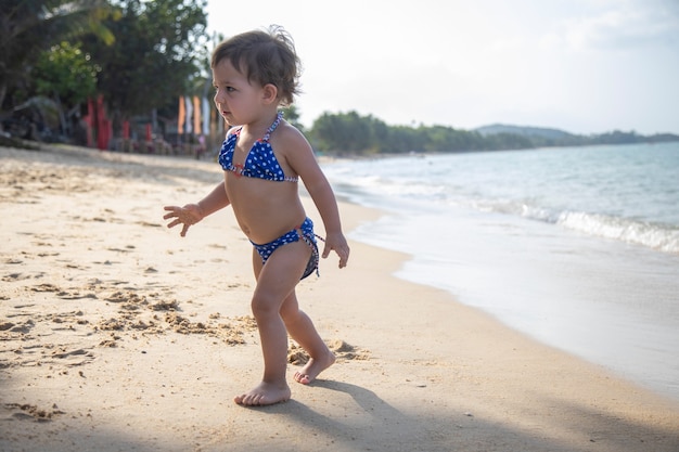 A menina bonita está correndo e brincando em uma praia perto do mar nas férias