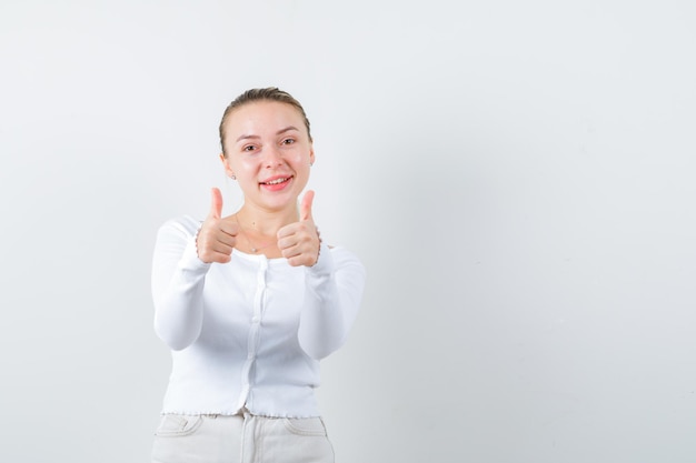 A menina bonita está mostrando um sinal excelente no fundo branco