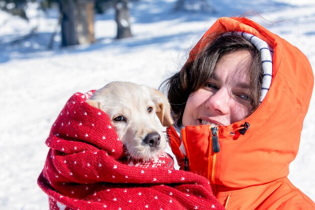 Foto a menina bonita sorri e aquece seu filhote no frio do inverno