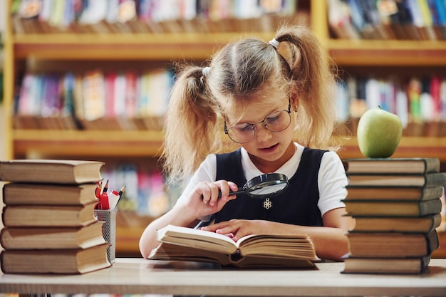 A menina bonitinha com rabo de cavalo está na biblioteca