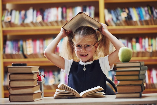 A menina bonitinha com rabo de cavalo está na biblioteca