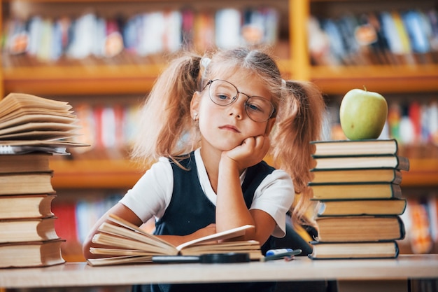 A menina bonitinha com rabo de cavalo está na biblioteca