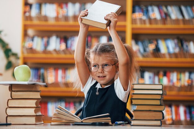 A menina bonitinha com rabo de cavalo está na biblioteca