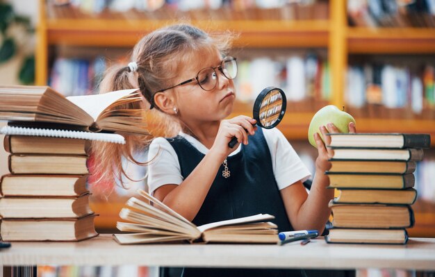 A menina bonitinha com rabo de cavalo está na biblioteca