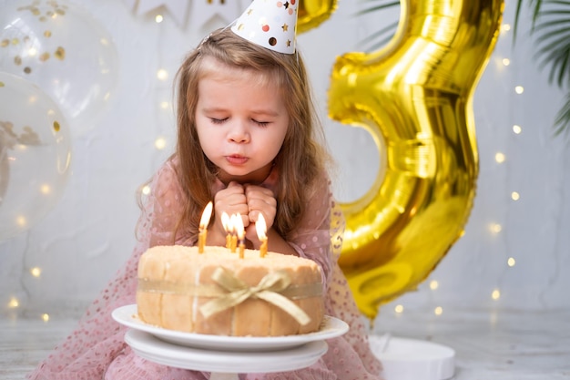 A menina bonitinha soprando velas no bolo de aniversário e comemorando o aniversário