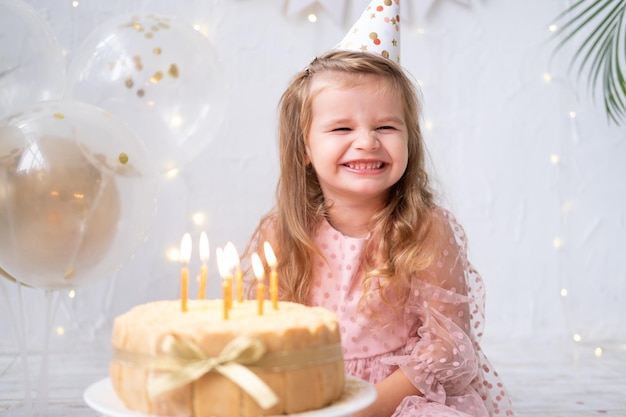 A menina bonitinha soprando velas no bolo de aniversário e comemorando o aniversário