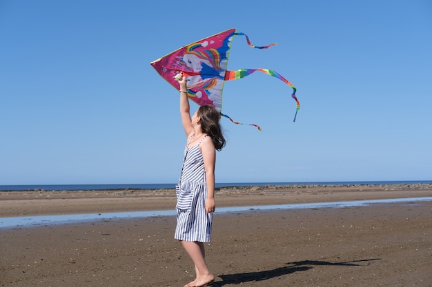 A menina brinca com uma pipa no mar