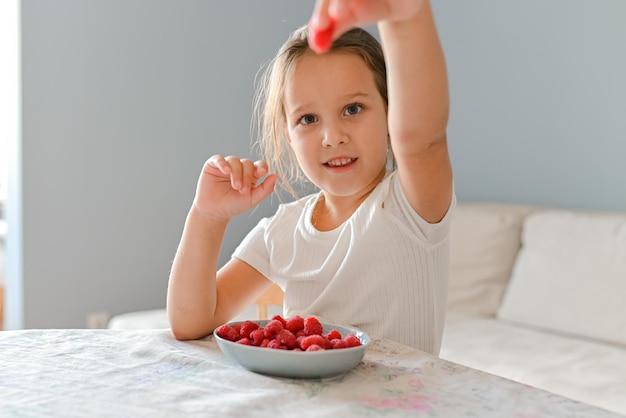 Foto a menina brincava com framboesas nos dedos