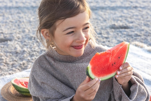 A menina closeup come melancia na praia