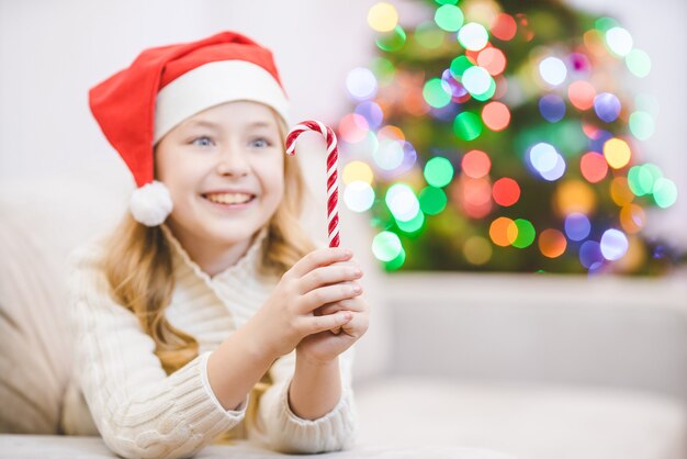 A menina com um doce estava deitada perto da árvore de natal