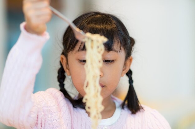 A menina come macarrão instantâneo.