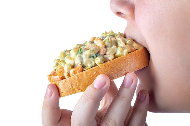 A menina come vinagrete de vários vegetais cozidos com pão, isolamento