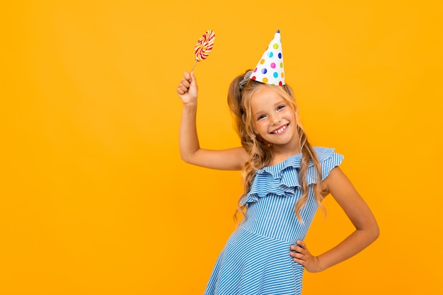 A menina consideravelmente caucasiano do teengager tem a festa do birthdau isolada na parede alaranjada