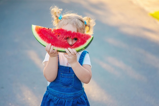 A menina da criança come melancia no verão Foco seletivo