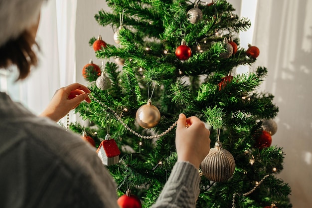 Foto a menina decora a árvore de natal para as férias preparando-se para o natal e o ano novo