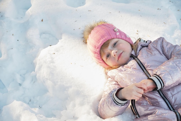 A menina deita na vista superior do espaço da cópia da neve