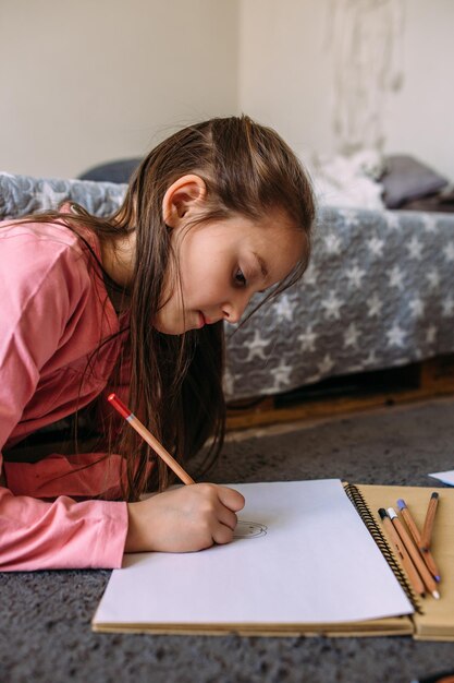 Foto a menina depois da escola joga em casa desenha com lápis e canetas de feltro