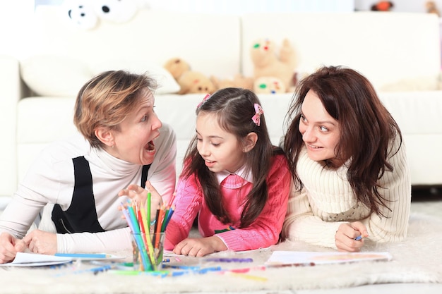 A menina desenha com sua mãe e avó